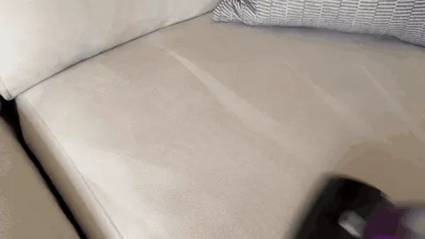 The cushion under the vacuum head shows the pass working: hair gone, fabric cleaner.