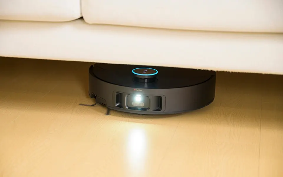 A retracted turret lets it reach dust most robots never touch; here it sits fully beneath a low sofa.