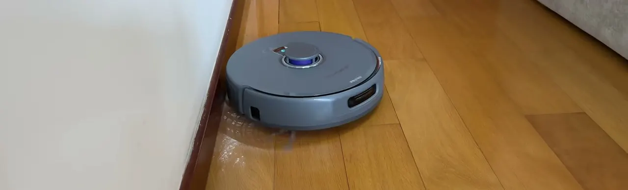 Wall-edge mopping can leave a wavy water trail; one is visible on the wood floor behind the robot.