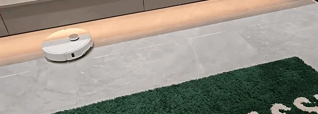 Pickup on hard floors clears in one pass; the misses are strays like the fluff at the rug edge.